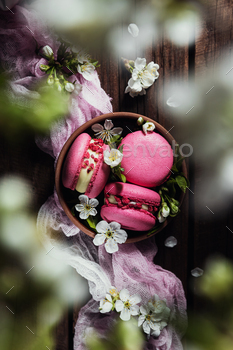 Top view on pink macaron cookies on wooden brown background with apple blossom